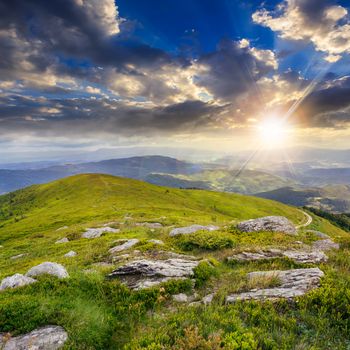 mountain landscape. valley with stones on the hillside. forest on the mountain under the beam of light falls on a clearing at the top of the hill at sunset