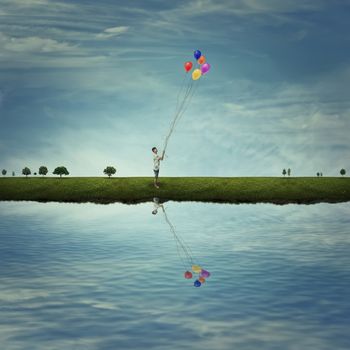 Young boy stand on a country meadow near the lake, holding some colorful balloons. Life joy, fun and happiness.