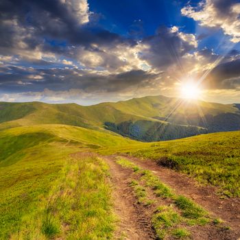 wide trail near the lawn in high mountains at sunset