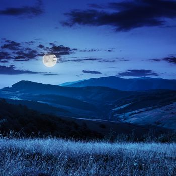 summer landscape. village on the hillside. forest on the mountain light fall on clearing on mountains at night in full moon light