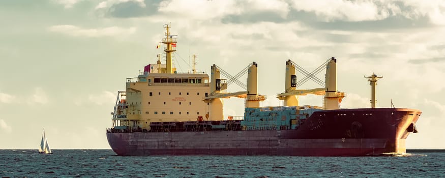 Red cargo ship moving entering the port of Riga