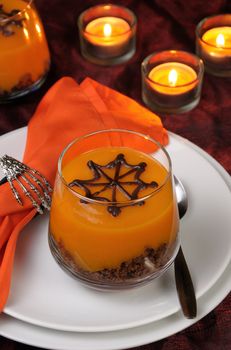 Dessert from biscuit and pumpkin cream in a glass of decorated chocolate  web for Halloween