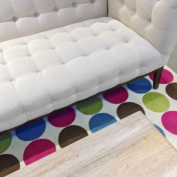 Elegant white sofa on a bright rug with colorful circles.