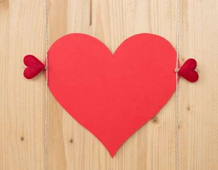 Two hearts with clothes pegs and red paper heart on a cord on wood