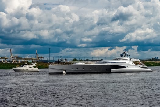 Large silver trimaran. Luxury yacht sailing by the river in Riga