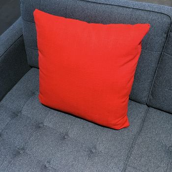 Vibrant red cushion decorating gray sofa. Modern style furniture.