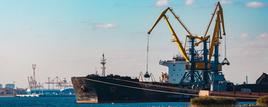 Black cargo ship loading with a coal at the port