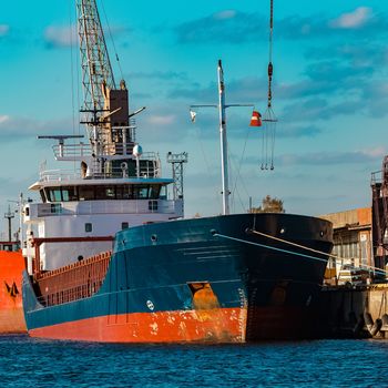 Blue cargo ship moored and loading at the port