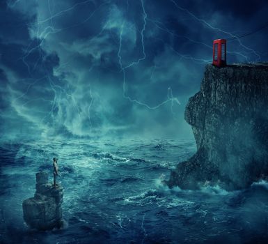 Lost man abandoned in the ocean standing on a rock island, in a stormy night with lightnings in the sky. Looking far at a cliff with a telephone box on the edge. Adventure, journey and hard determination concept.