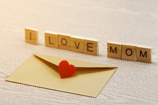 I love mom wording with red heart sign and gold envelope on corrugated paper
 background, Mother's day concept.