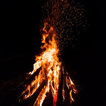 Campfire with flying sparks isolated on black background