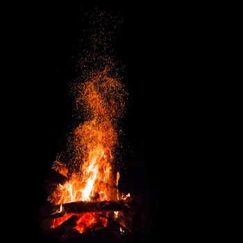 Campfire with flying sparks isolated on black background