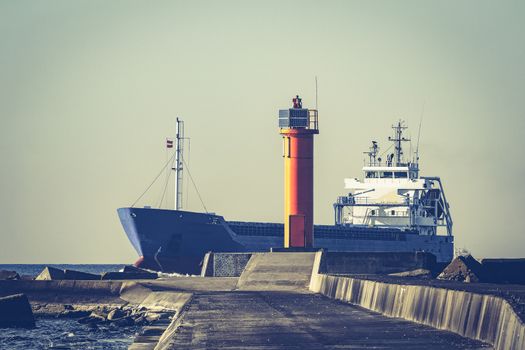Blue cargo ship sailing against the breakwater dam