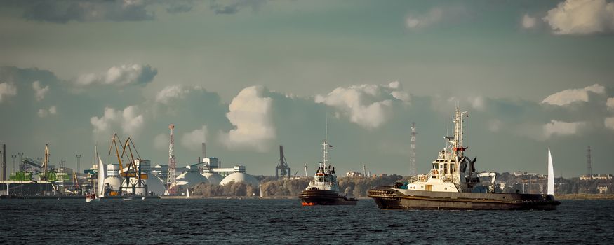 Two tug ships are accepting cargo vessel at Daugava river