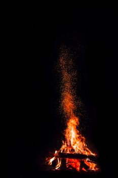 Campfire with flying sparks isolated on black background