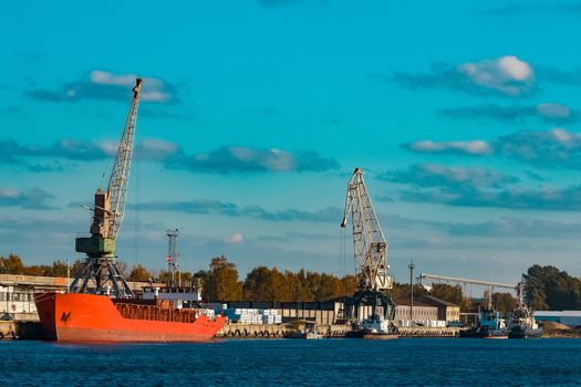 Red cargo ship moored and loading in the port