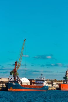 Blue cargo ship moored and loading at the port