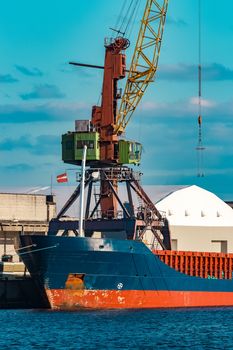 Blue cargo ship moored and loading at the port