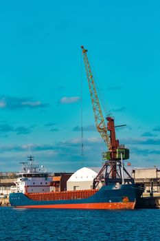 Blue cargo ship moored and loading at the port