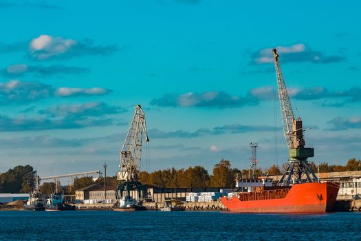 Red cargo ship moored and loading in the port