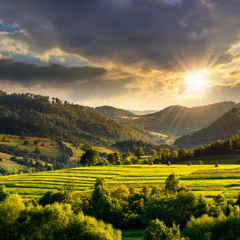 Summer land scape . Stack of hay on a green meadow in the mountains at sunset