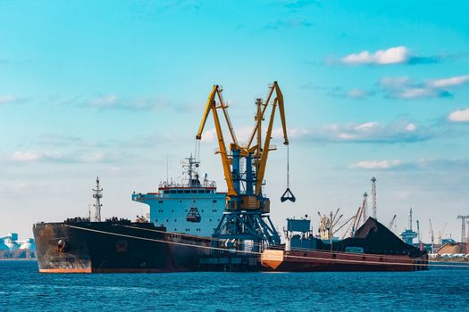 Black cargo ship loading with a coal at the port