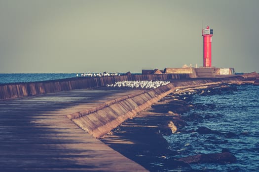 Red lighthouse on breakwater jetty at Baltic sea