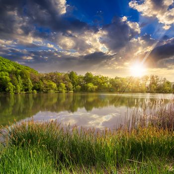 view on lake near the forest on mountain background at sunset