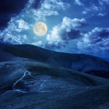 lake near the path in grass at the top of the mountain at night in full moon light