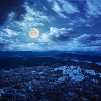 white sharp stones on the hillside on top of mountain range at night in full moon light