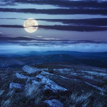 white sharp stones on the hillside on top of mountain range at night in full moon light