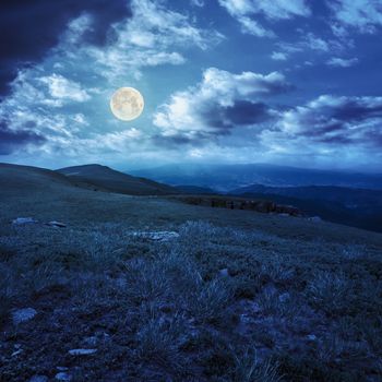 white sharp stones on the hillside of high mountain range at night in full moon light