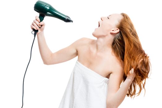 Red-haired woman dries hair with a hairdryer on a white background