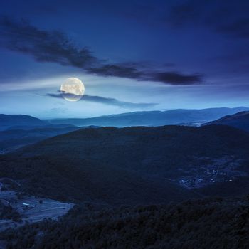 summer landscape. village on the hillside. forest on the mountain light fall on clearing on mountains at night in full moon light