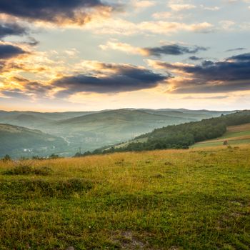 Stack of hay on a green meadow in the mountains in the morning under a blue summer sky slope at sunrise