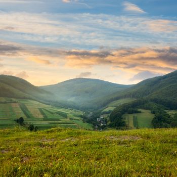 Stack of hay on a green meadow in the mountains in the morning under a blue summer sky at sunrise