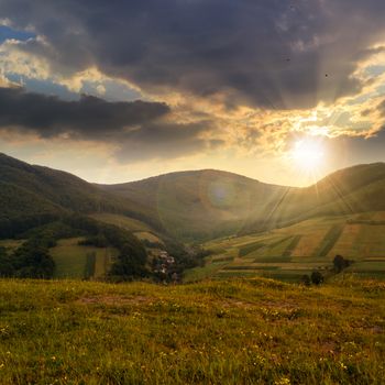 Stack of hay on a green meadow in the mountains in the morning under a blue summer sky at sunset