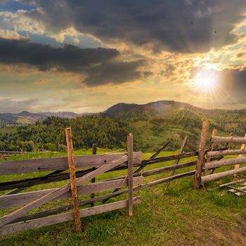 autumn landscape. fence near the meadow path on the hillside. forest in fog on the mountain. at sunset