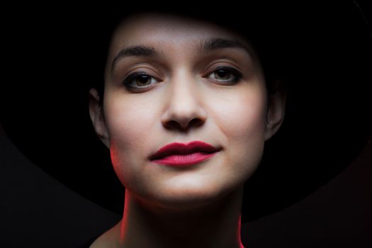 portrait of a beautiful girl with red lipstick and black hat