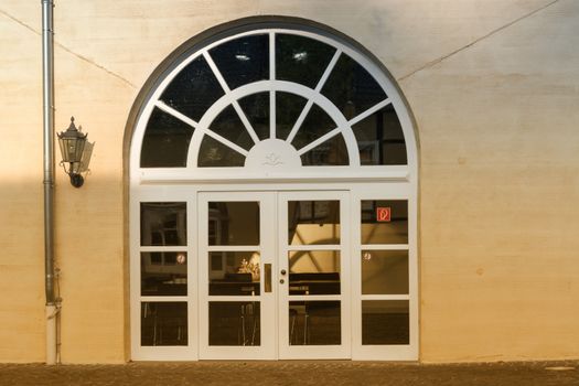 New large round arch door with rungs in a yellow plastered house wall.