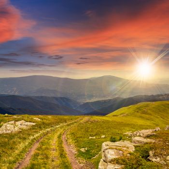 road among white sharp stones on the hillside on top of mountain range at sunset