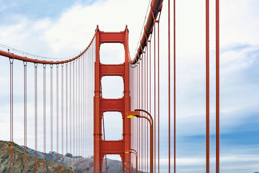 Golden Gate Bridge Tower with street lamps and hills in the distance