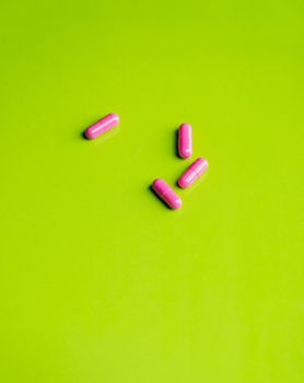 pink pills and medicine over a green table and backrgound