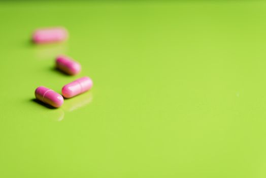 pink pills and medicine over a green table and backrgound