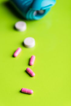 pink pills and medicine over a green table and backrgound