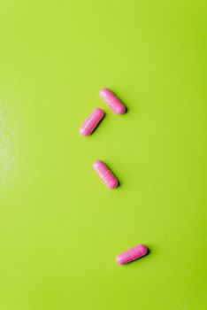 pink pills and medicine over a green table and backrgound