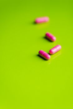 pink pills and medicine over a green table and backrgound