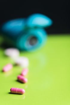 pink pills and medicine over a green table and backrgound