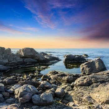 calm sea wave on rocky shore with boulders