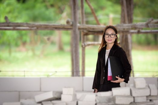 Businesswoman standing holding a file  in a brick building.